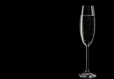 Glass of champagne on black background, space for text