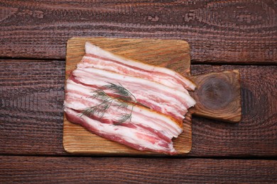 Photo of Slices of tasty pork fatback with dill on wooden table, top view