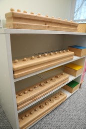 Shelving unit with different wooden geometric puzzles in room. Montessori toy