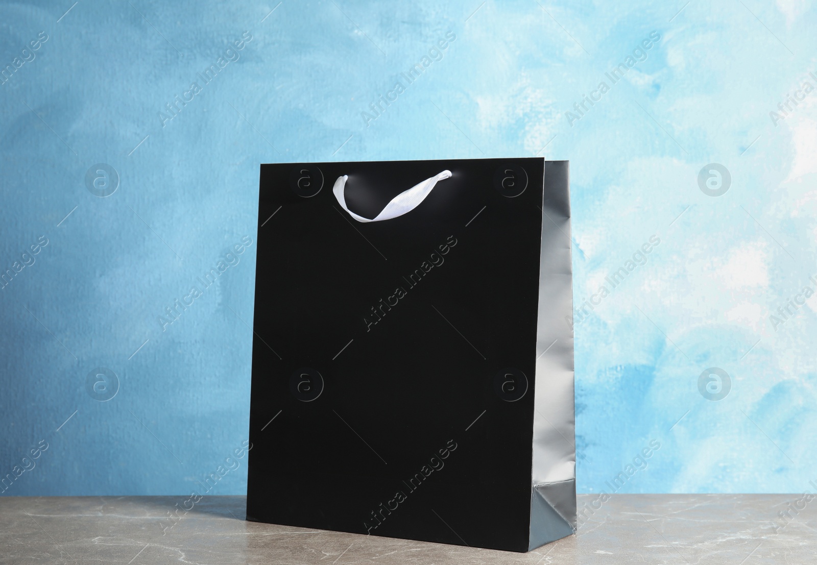 Photo of Paper shopping bag on table against color background. Mock up for design