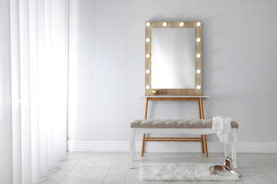 Photo of Stylish mirror with lamps near light wall in room