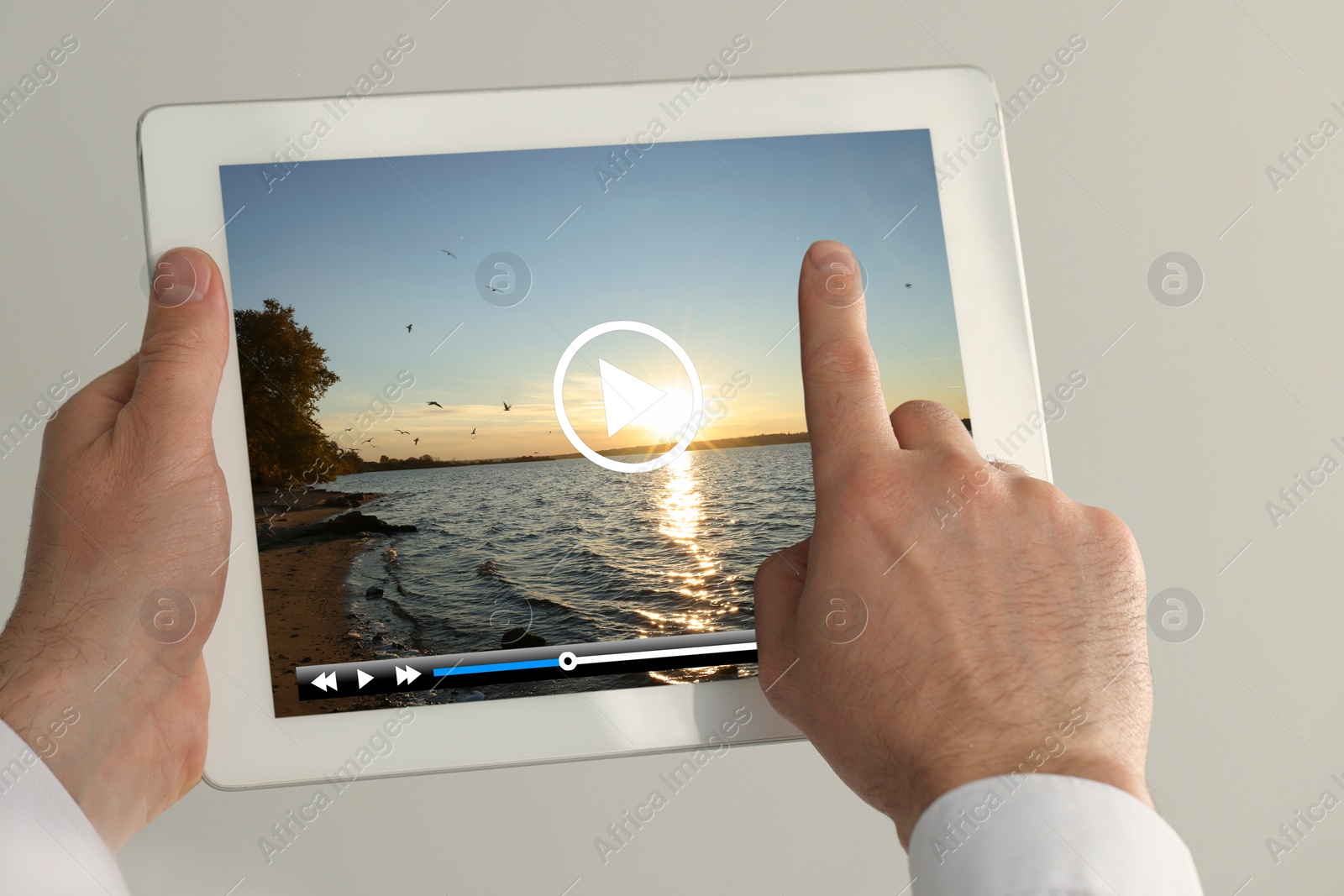 Image of Man touching tablet screen to play video on light background, closeup