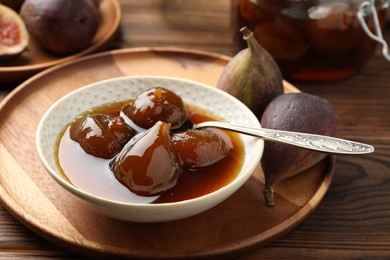 Bowl of tasty sweet jam and fresh figs on wooden table