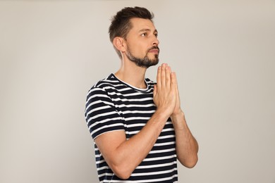 Photo of Man with clasped hands praying on light grey background