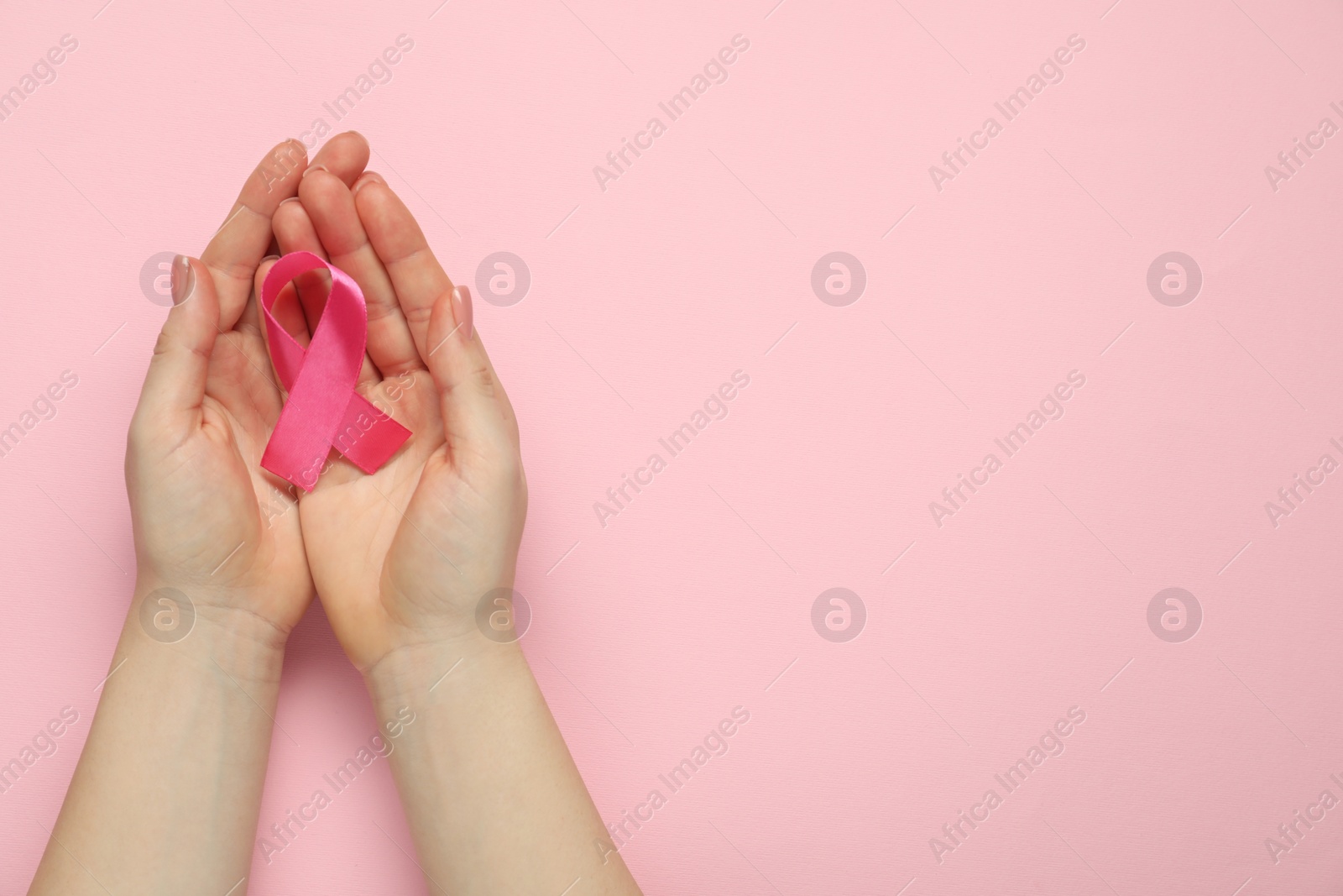 Photo of Breast cancer awareness. Woman with pink ribbon on color background, top view. Space for text