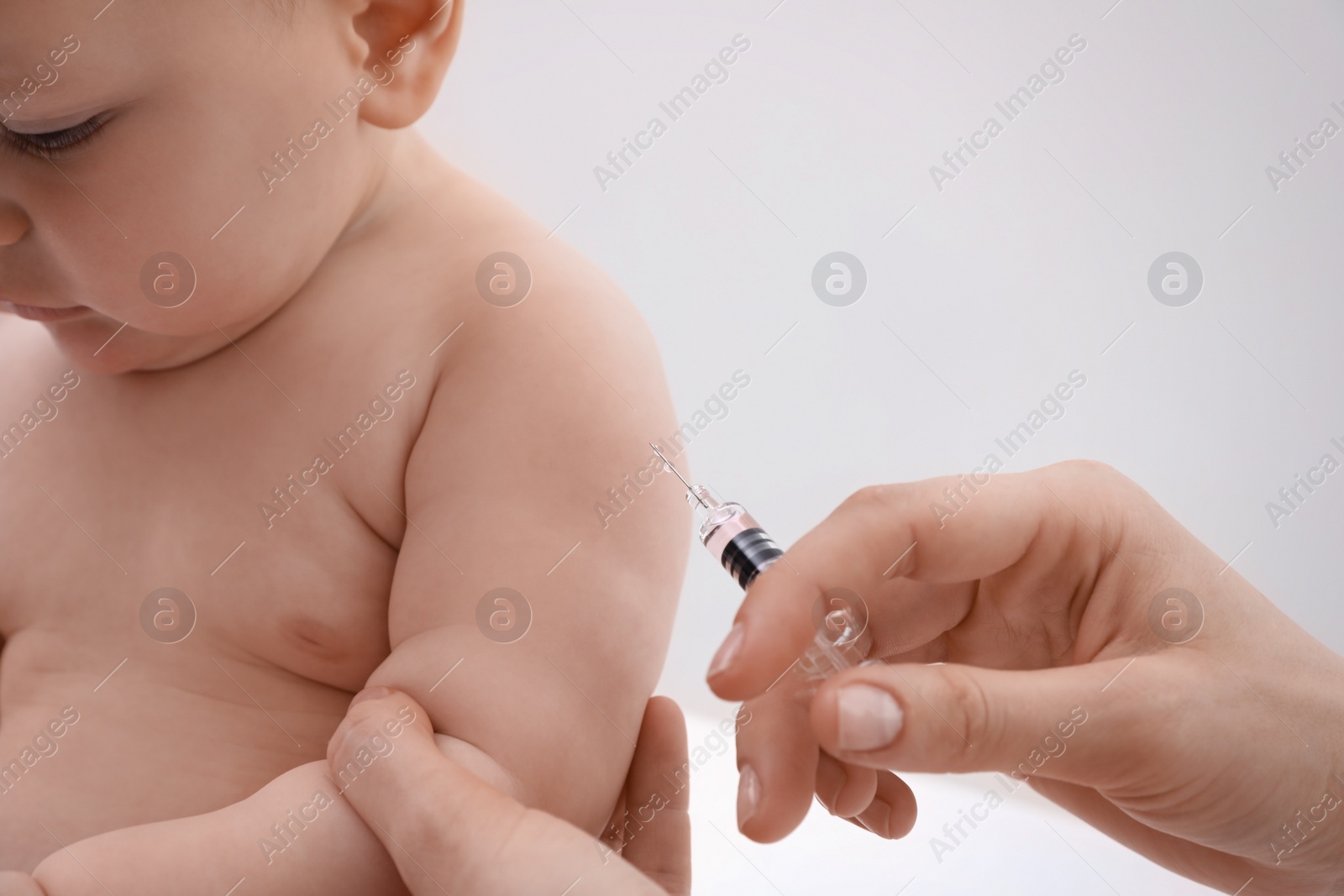 Photo of Doctor vaccinating baby against light background, closeup. Health care