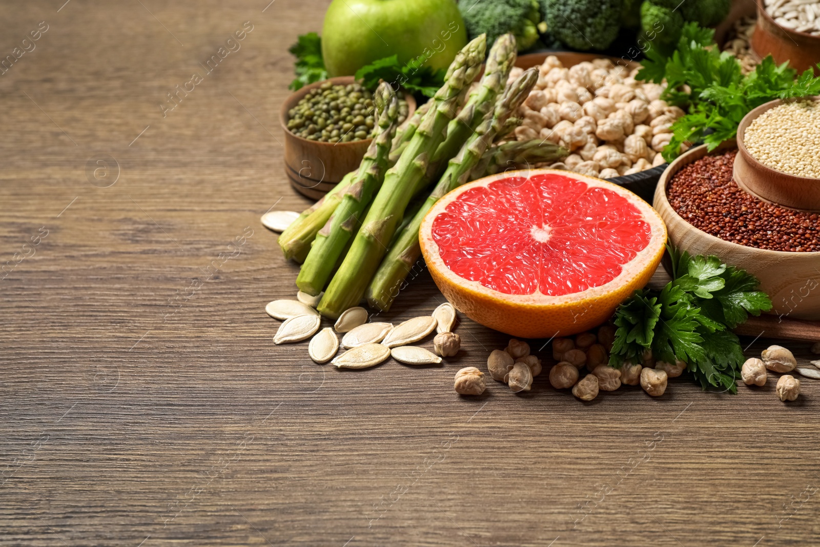 Photo of Fresh vegetables, grapefruit and seeds on wooden table, space for text