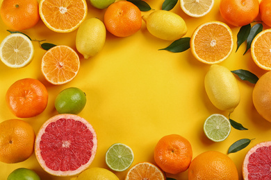 Flat lay composition with tangerines and different citrus fruits on yellow background. Space for text