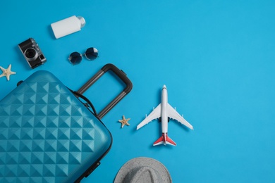 Flat lay composition with suitcase and travel accessories on light blue background. Summer vacation
