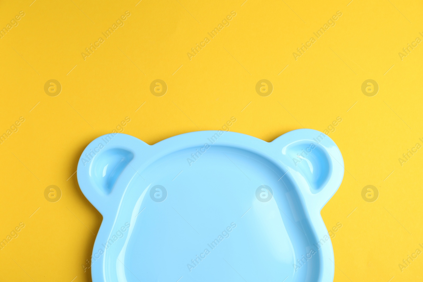 Photo of Cute animal shaped plate on yellow background, top view. Serving baby food