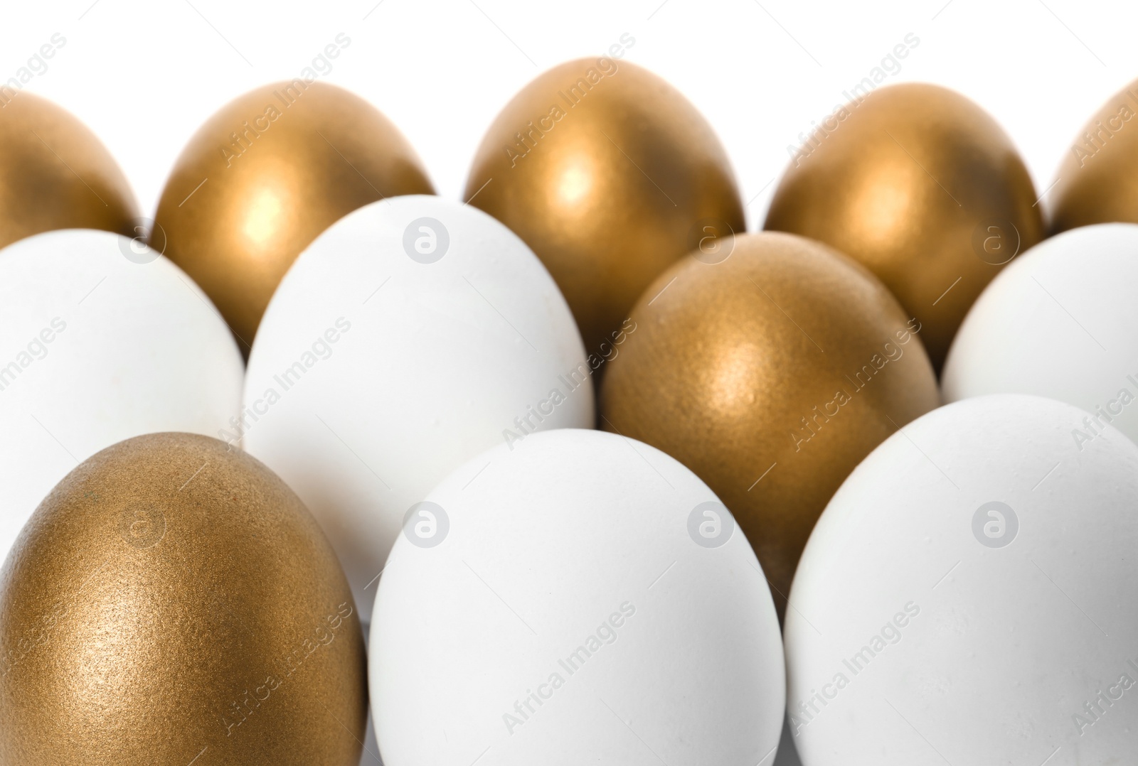 Photo of Golden eggs among others on white background