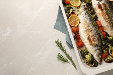 Photo of Delicious fish with vegetables and lemon in baking dish on light marble table, top view. Space for text