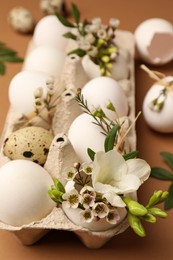 Photo of Festive composition with eggs and floral decor on brown background, closeup. Happy Easter