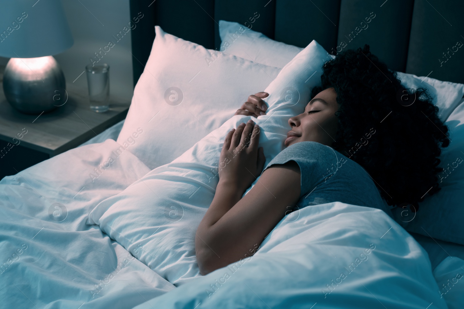 Photo of Young woman sleeping in soft bed at night