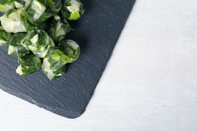 Slate plate with lime and mint ice cubes on light table, top view. Space for text