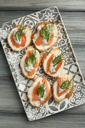 Photo of Tasty canapes with salmon, cucumber, cream cheese and dill on wooden table, top view