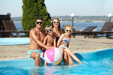 Photo of Happy family with inflatable ball at poolside on sunny summer day