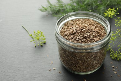 Dry seeds and fresh dill on black table, closeup. Space for text