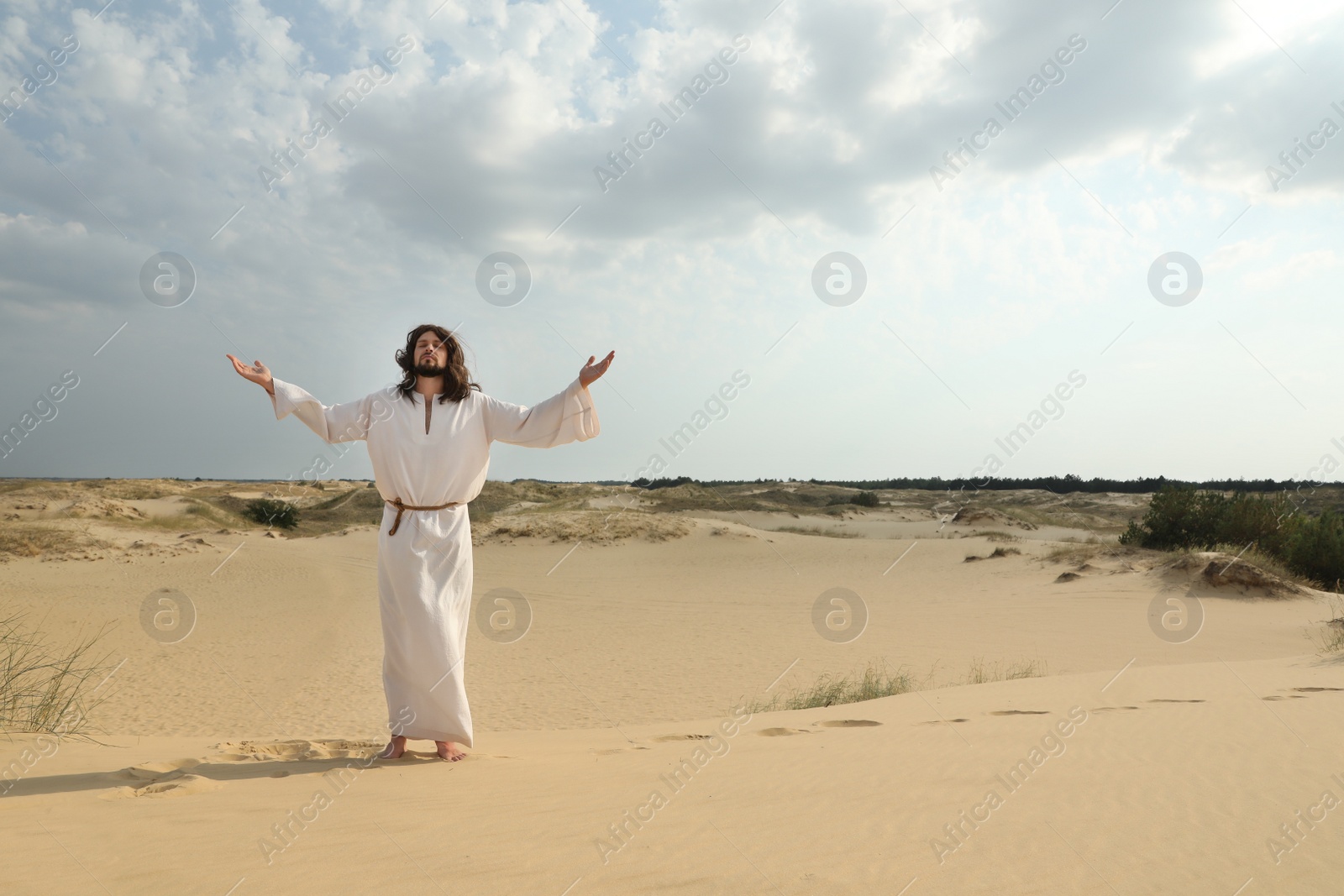 Photo of Jesus Christ raising hands in desert. Space for text