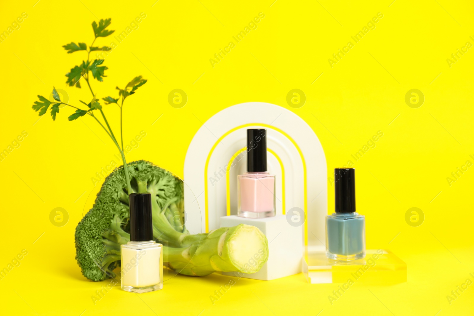Photo of Stylish presentation of beautiful nail polishes in bottles on yellow background