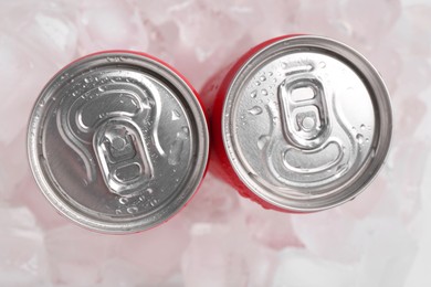 Photo of Energy drinks in wet cans on ice cubes, flat lay