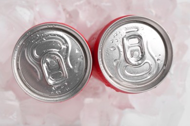 Energy drinks in wet cans on ice cubes, flat lay