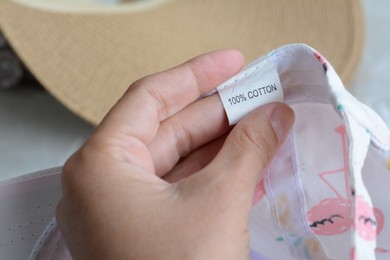 Photo of Woman holding clothing label on garment, closeup