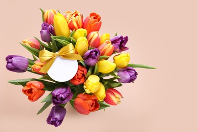 Bouquet of beautiful colorful tulips with blank card on beige background, top view and space for text. Birthday celebration
