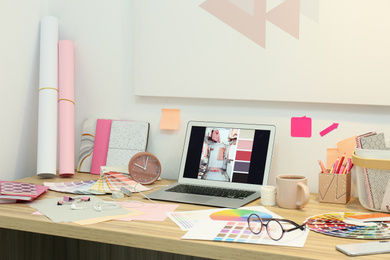 Photo of Designer's workplace with modern laptop and color palettes 