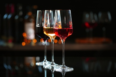 Photo of Row of glasses with different wines on bar counter against blurred background