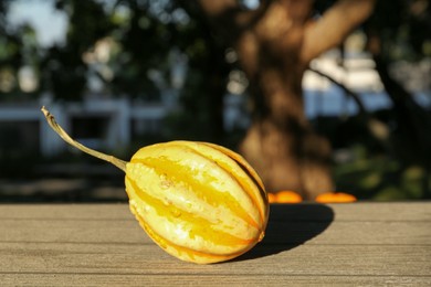 Photo of Whole ripe pumpkin on wooden table outdoors