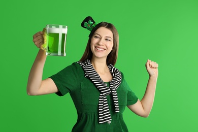 Image of Happy woman in St. Patrick's Day outfit with beer on green background