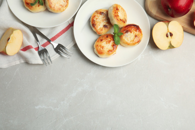 Delicious cottage cheese pancakes and apples on grey marble table, flat lay. Space for text