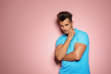 Young man with trendy hairstyle posing on color background