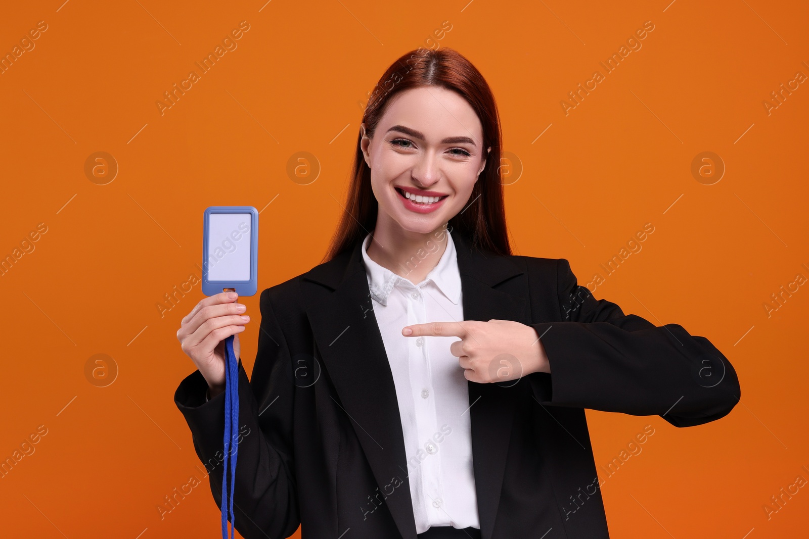 Photo of Smiling woman pointing at vip pass badge on orange background