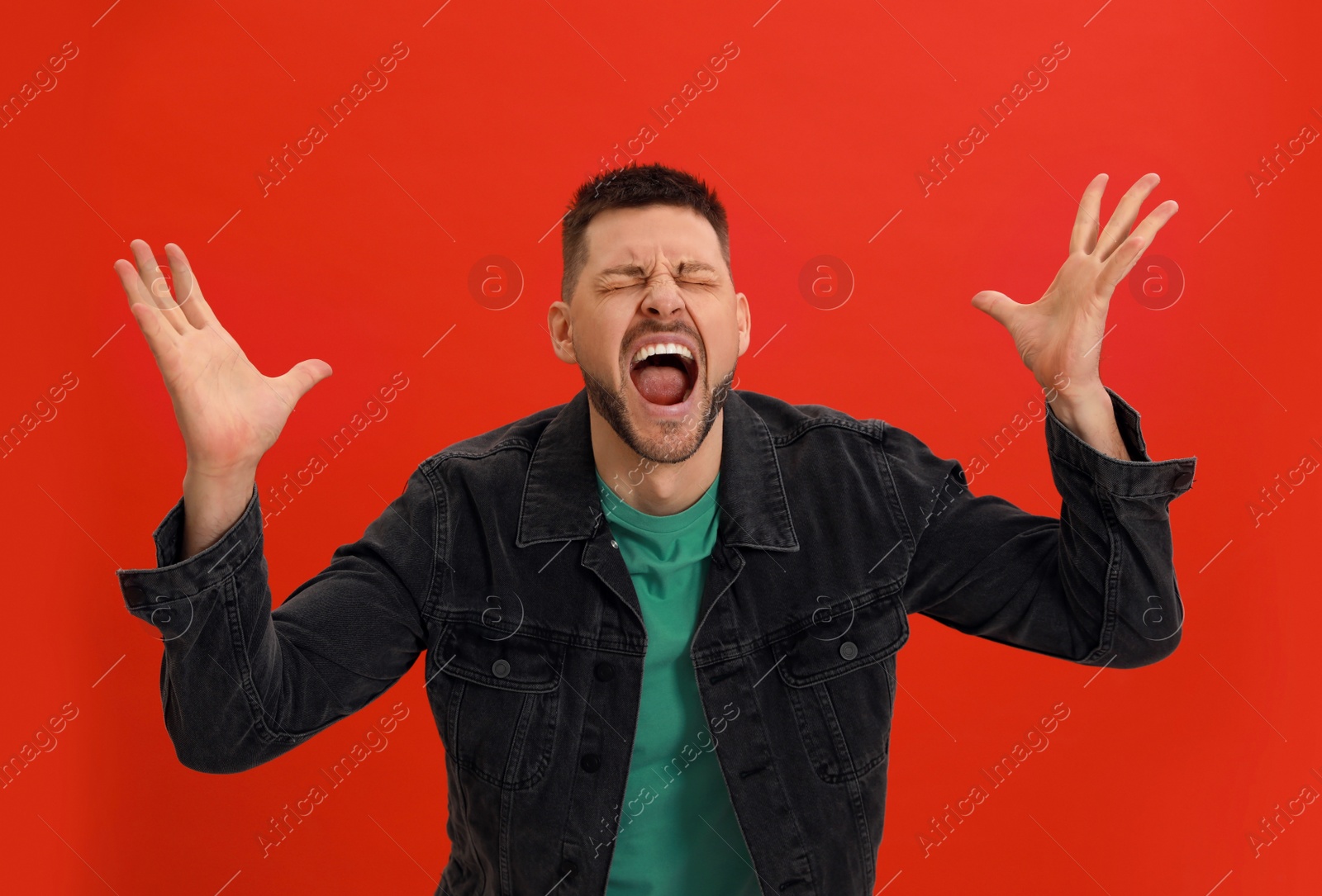 Photo of Angry man yelling on red background. Hate concept