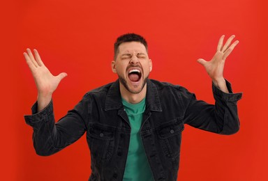 Photo of Angry man yelling on red background. Hate concept