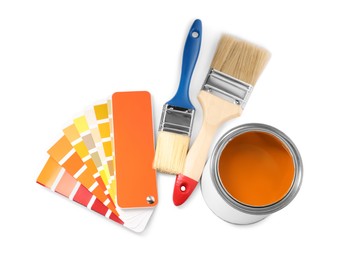 Photo of Can with orange paint, brushes and palette samples on white background, above view