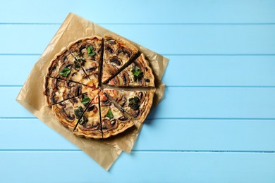 Delicious quiche with mushrooms and parsley on light blue wooden table, top view. Space for text