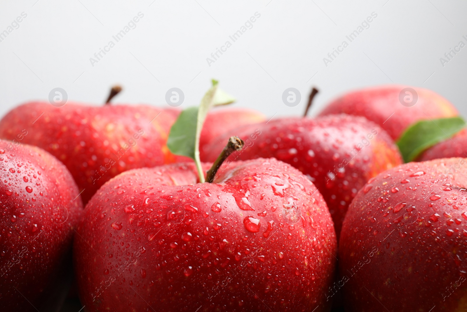 Photo of Delicious ripe red apples with water drops on light grey background, closeup