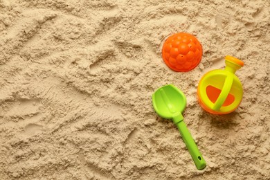 Flat lay of beach toy kit on sand, space for text. Outdoor play