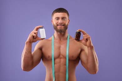 Athletic young man with measuring tape and bottles of supplements on purple background. Weight loss