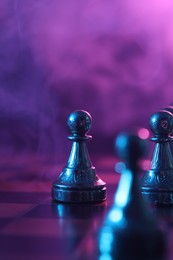 Photo of Chess pawn on checkerboard in color light, selective focus. Space for text
