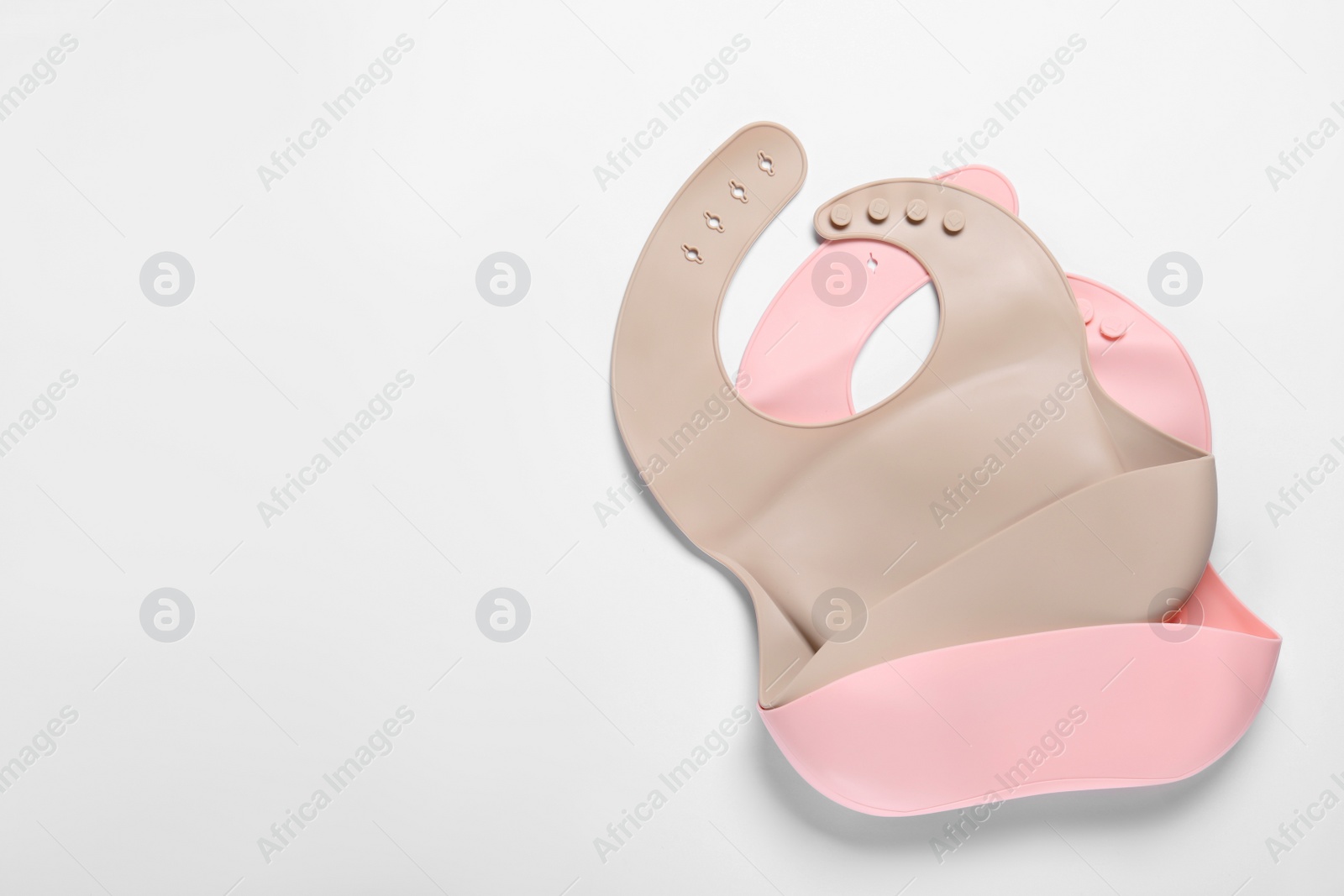 Photo of Color silicone baby bibs on white background, top view