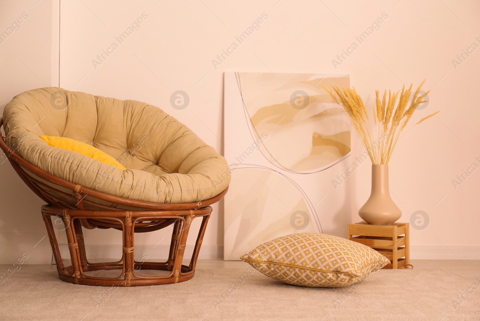 Photo of Vase with decorative dried plants and painting near papasan chair in stylish room interior