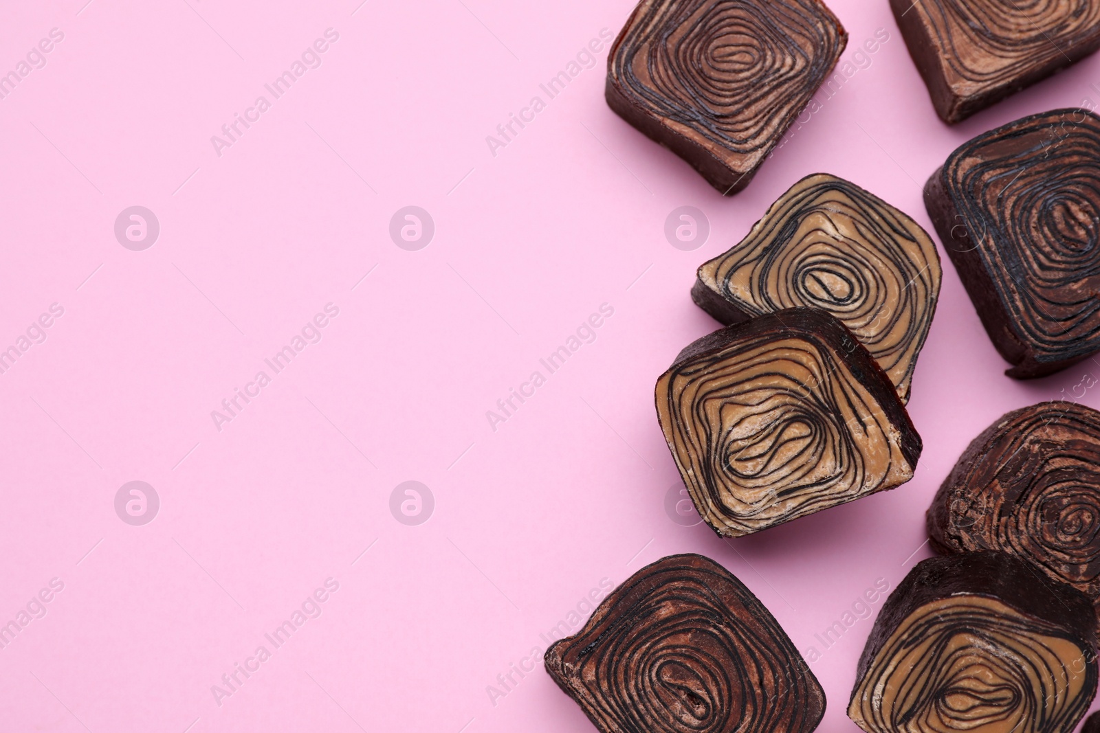 Photo of Different tasty chocolate candies on pink background, flat lay. Space for text