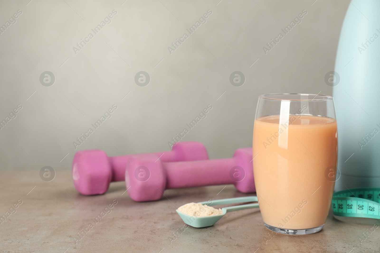 Photo of Tasty shake, dumbbells and powder on gray table, space for text. Weight loss