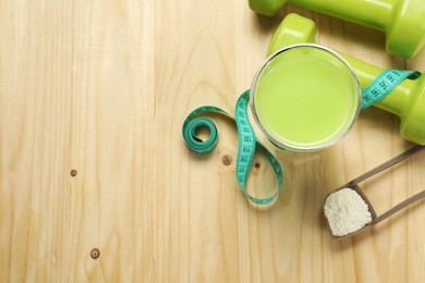 Photo of Tasty shake, dumbbells, measuring tape and powder on wooden table, flat lay with space for text. Weight loss