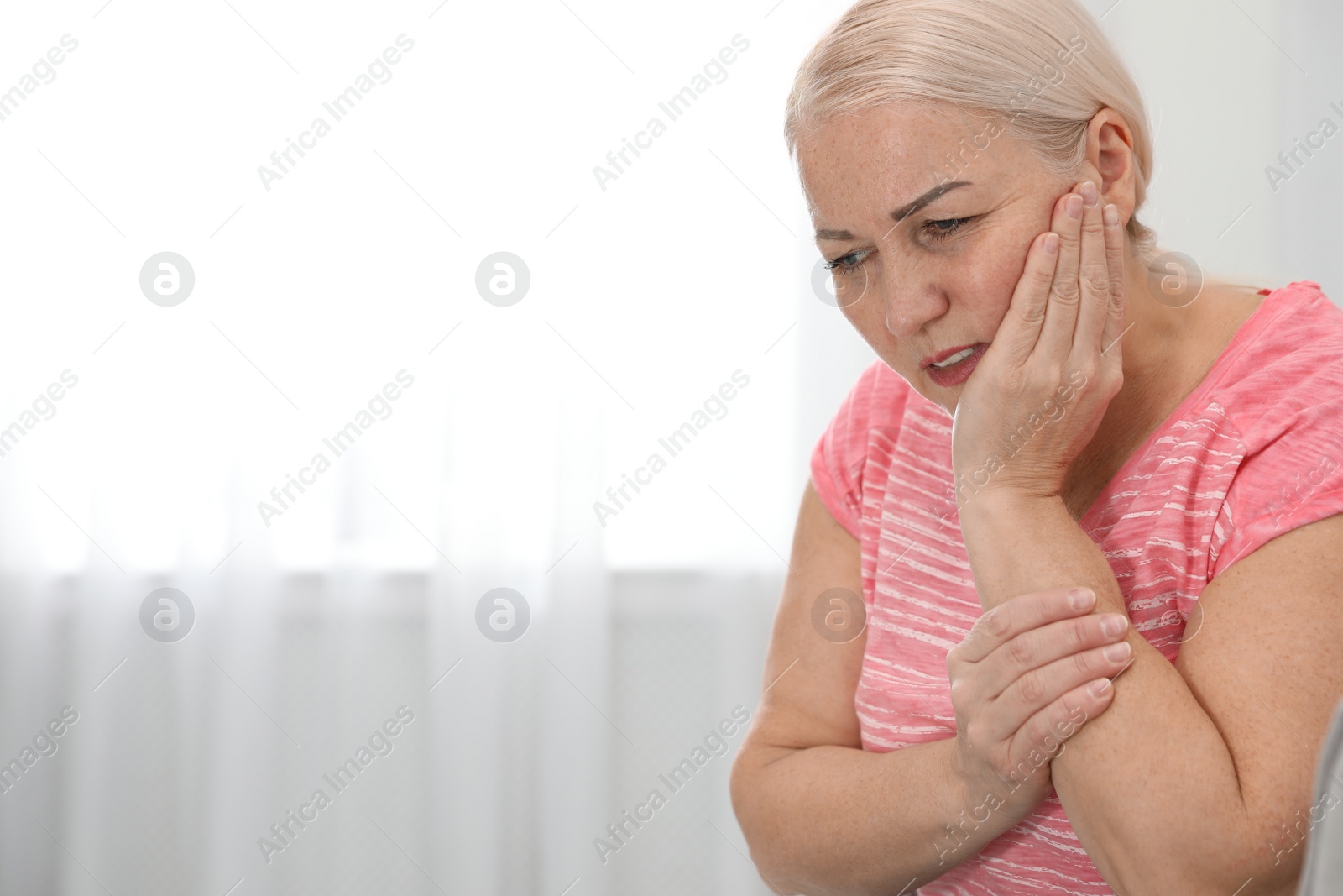 Photo of Mature woman suffering from strong tooth pain at home, space for text