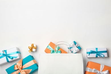 Flat lay composition with shopping bag and gifts on white background